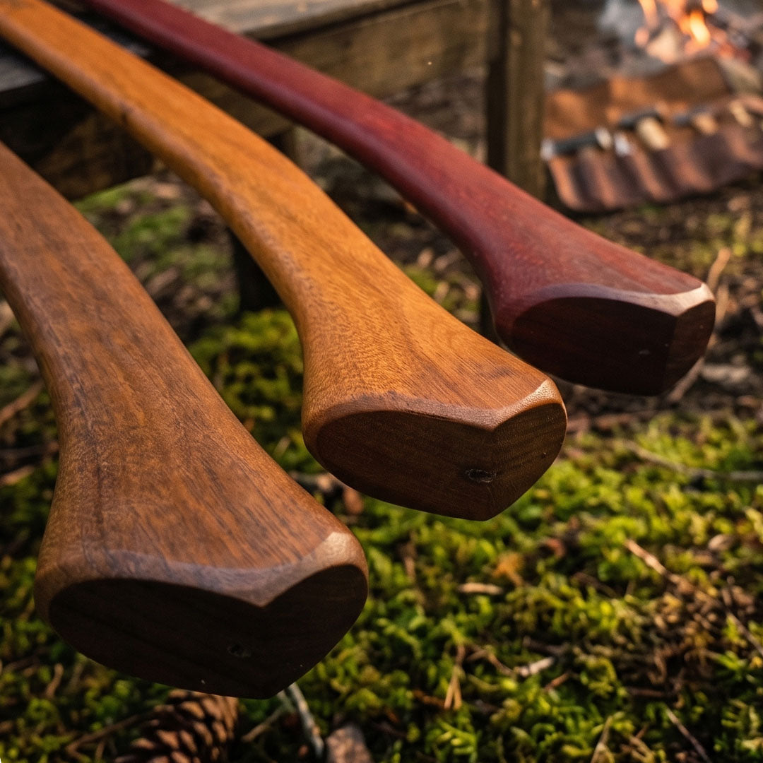 Three Outbaxe spotted gum axe handles on a mossy background